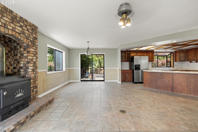 11185 SE Saint Lucy Ln, Happy Valley, OR 97086 - kitchen with stainless steel fridge, wainscoting, light countertops, light tile patterned floors, and a peninsula
