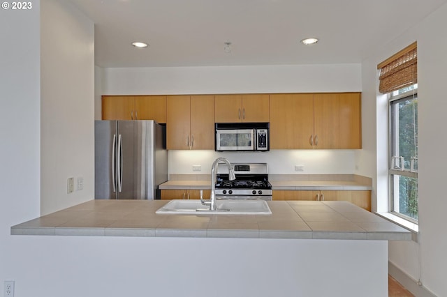 kitchen with tile countertops, a wealth of natural light, stainless steel appliances, and kitchen peninsula