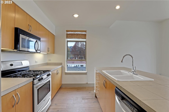 kitchen featuring appliances with stainless steel finishes, sink, and light hardwood / wood-style flooring