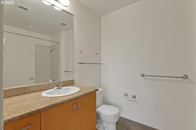 bathroom with tile flooring, toilet, and vanity