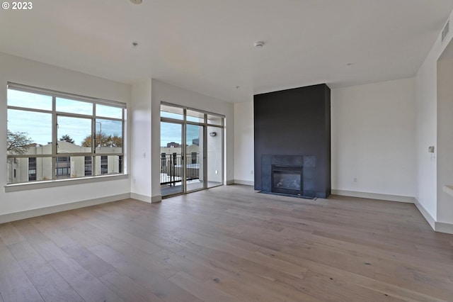 unfurnished living room with a tiled fireplace and light wood-type flooring