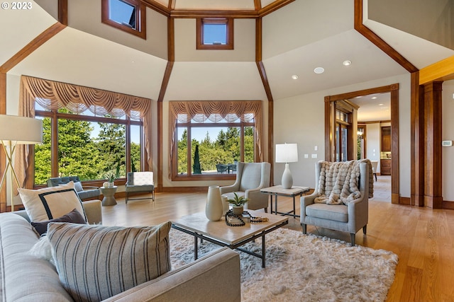 living room with a towering ceiling, a wealth of natural light, and light wood-type flooring