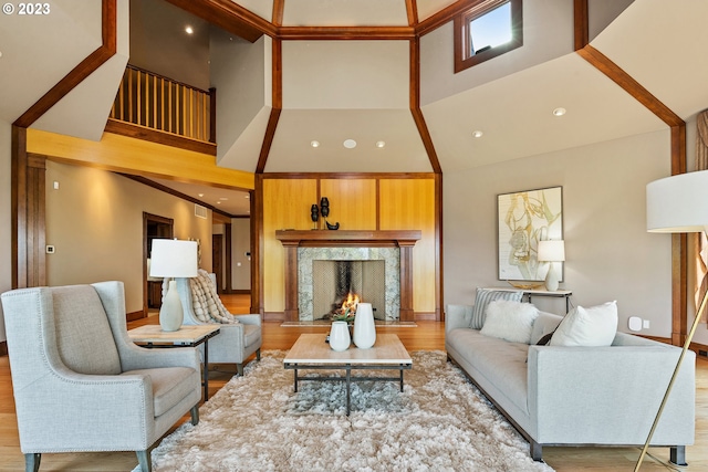 living room with a high end fireplace, light hardwood / wood-style floors, and a high ceiling