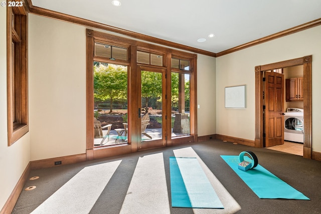 exercise room with crown molding, washer / dryer, and light colored carpet