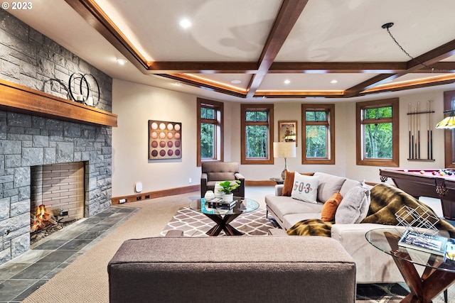 living room featuring coffered ceiling, a stone fireplace, and beam ceiling