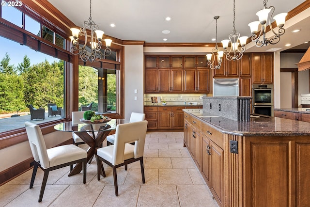 kitchen with backsplash, a notable chandelier, appliances with stainless steel finishes, dark stone counters, and a kitchen island