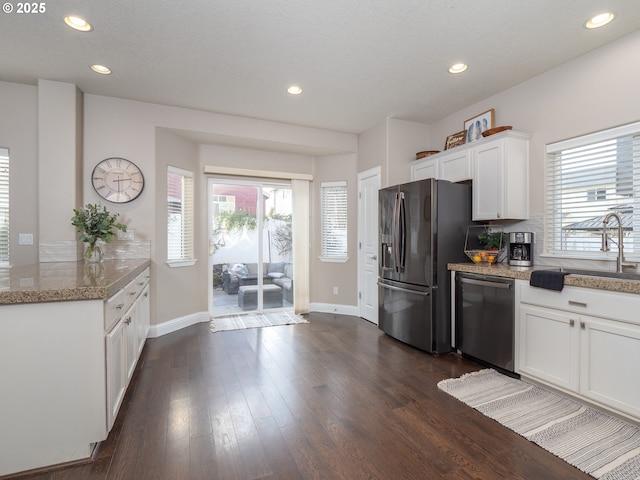 kitchen with black fridge, stainless steel dishwasher, a healthy amount of sunlight, and white cabinets