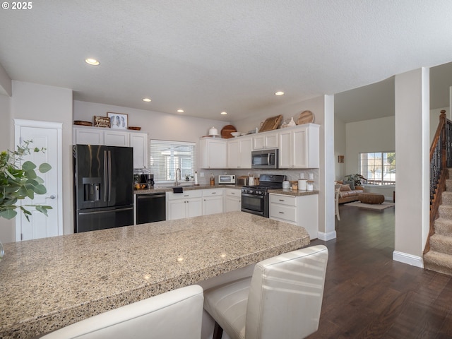 kitchen with white cabinetry, plenty of natural light, black appliances, and a kitchen breakfast bar