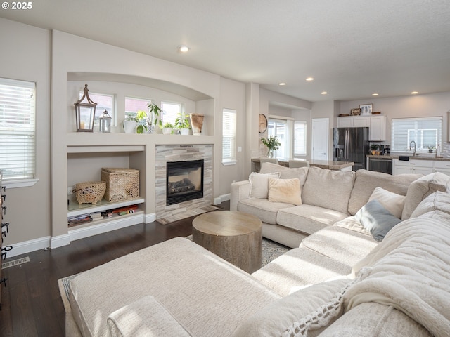 living room with dark wood-type flooring and a tile fireplace