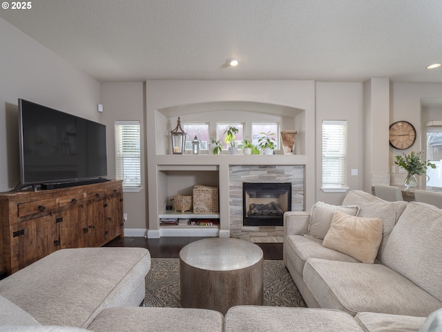 living room with hardwood / wood-style floors, built in shelves, plenty of natural light, and a tile fireplace