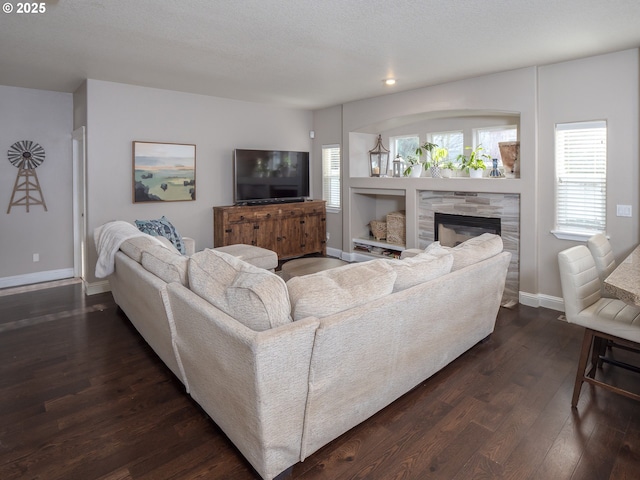 living room with a stone fireplace and dark hardwood / wood-style flooring