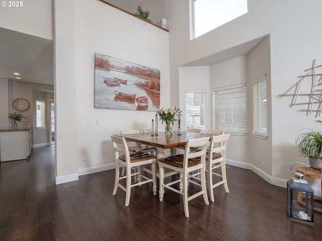 dining room with a high ceiling and dark hardwood / wood-style flooring