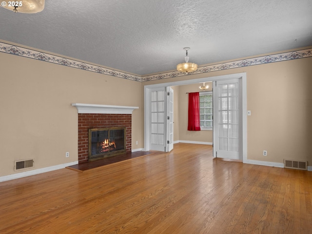 510 SE Shafford St, Estacada, OR 97023 - unfurnished living room featuring wood finished floors, an inviting chandelier, a fireplace, and visible vents