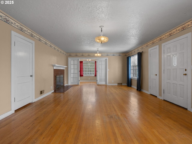 510 SE Shafford St, Estacada, OR 97023 - unfurnished living room with baseboards, light wood-style flooring, a textured ceiling, a brick fireplace, and visible vents