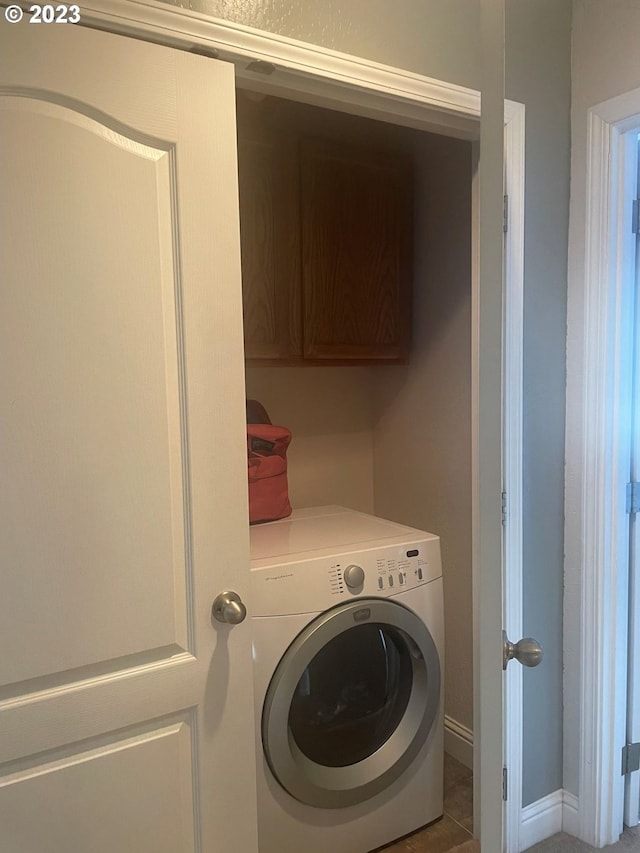 washroom with washer / clothes dryer, cabinets, and tile flooring