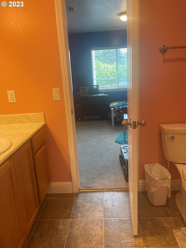 bathroom featuring toilet, tile flooring, and vanity