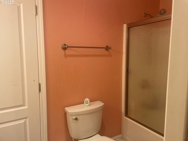 bathroom featuring combined bath / shower with glass door and toilet