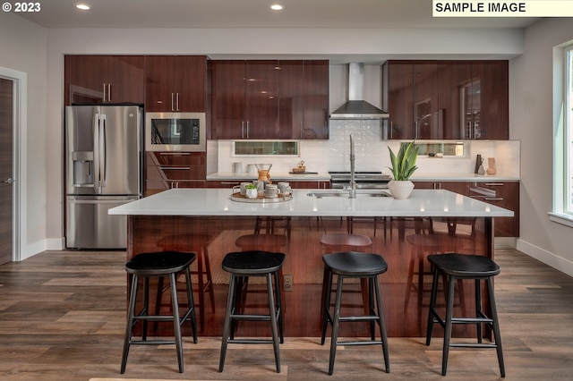 kitchen with stainless steel refrigerator with ice dispenser, a kitchen island with sink, built in microwave, and wall chimney exhaust hood