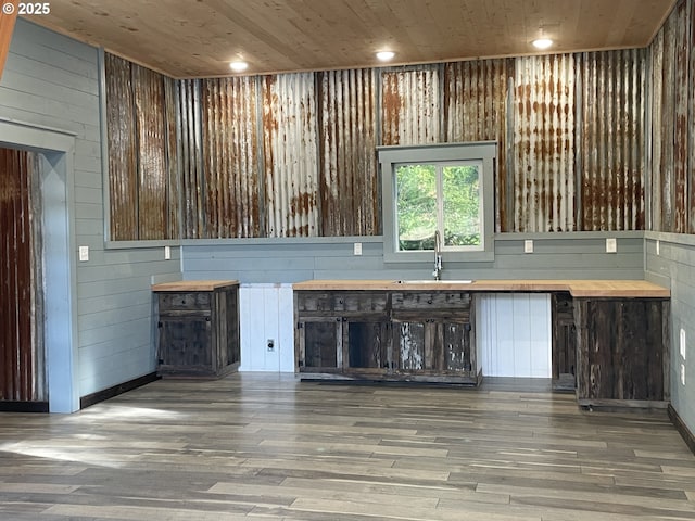 interior space featuring a sink, wood finished floors, wooden walls, and wooden ceiling