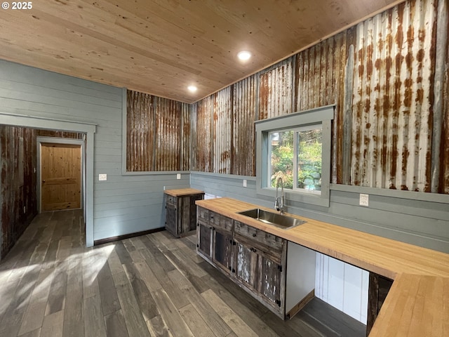 kitchen with butcher block countertops, a sink, dark wood finished floors, wooden ceiling, and wood walls