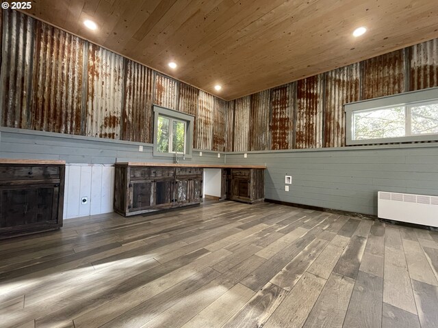 unfurnished living room featuring hardwood / wood-style floors, recessed lighting, radiator, a fireplace, and wood ceiling