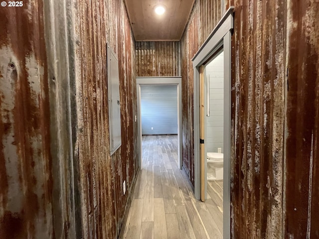 corridor featuring light wood-style flooring and wooden walls