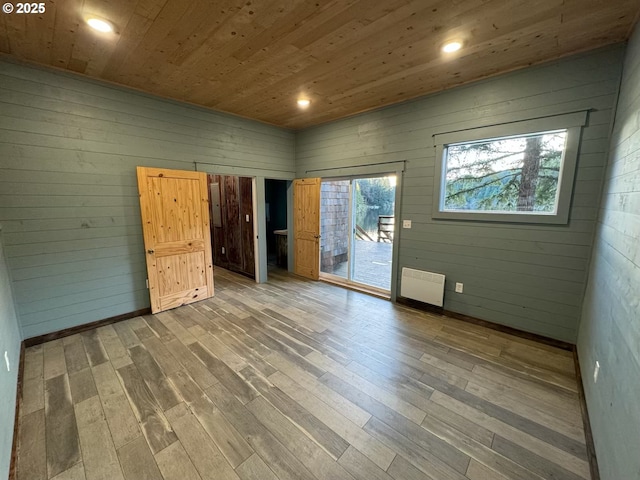 empty room with recessed lighting, wood finished floors, radiator, and wooden ceiling