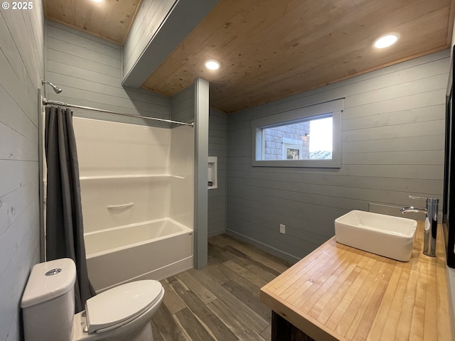 bathroom featuring a sink, toilet, wood finished floors, and wooden walls