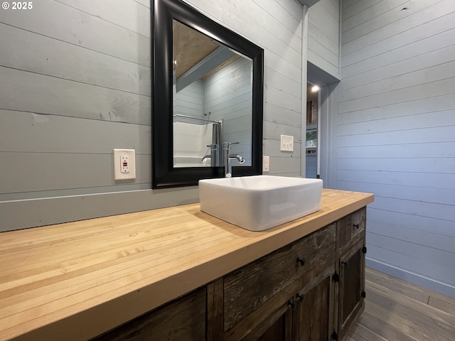 bathroom with vanity, wood finished floors, and wood walls