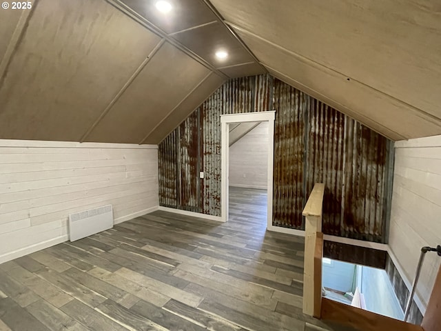 bonus room featuring wood walls, wood finished floors, radiator heating unit, and vaulted ceiling