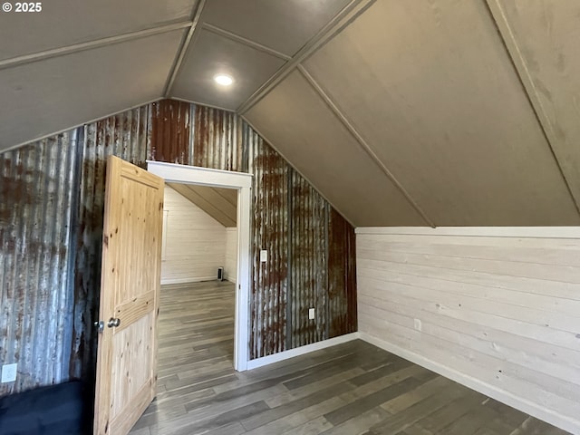 additional living space featuring vaulted ceiling, wood finished floors, and wood walls