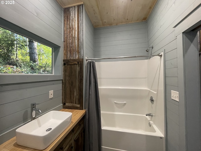 bathroom with a sink, wooden ceiling, wood walls, and shower / bath combo