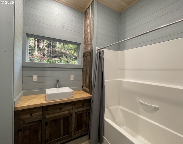 full bathroom featuring shower / bathtub combination with curtain, wood walls, and vanity