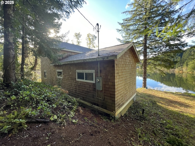 view of side of property with a shingled roof and a water view