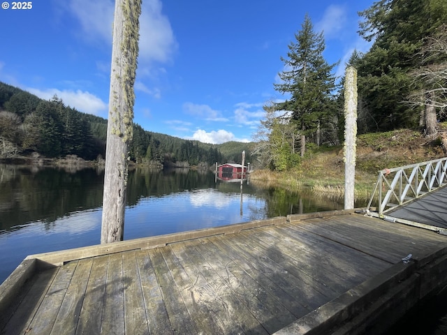 view of dock with a forest view and a water view