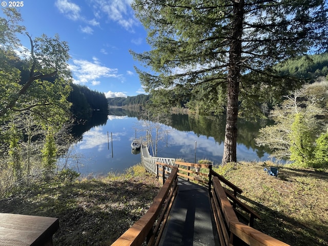 view of dock with a wooded view and a water view