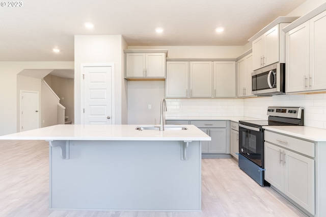 kitchen featuring appliances with stainless steel finishes, sink, a center island with sink, and a kitchen bar