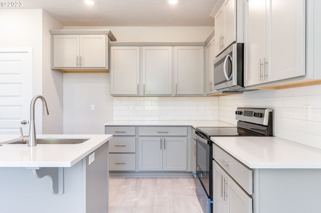 kitchen with gray cabinets, tasteful backsplash, electric range oven, and sink