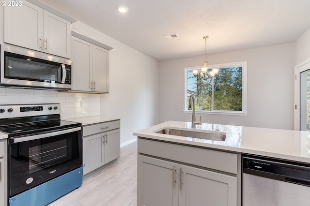 kitchen featuring pendant lighting, sink, gray cabinets, appliances with stainless steel finishes, and backsplash