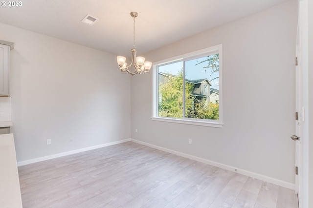 unfurnished dining area with a chandelier and light wood-type flooring