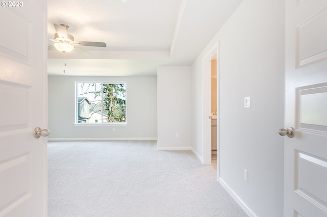 carpeted empty room with a raised ceiling and ceiling fan