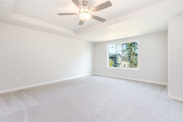 spare room featuring ceiling fan, a raised ceiling, and carpet floors