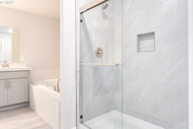 bathroom with shower with separate bathtub, wood-type flooring, and vanity