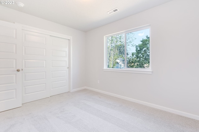 unfurnished bedroom with light carpet and a closet