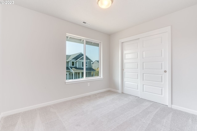 unfurnished bedroom with light carpet and a closet