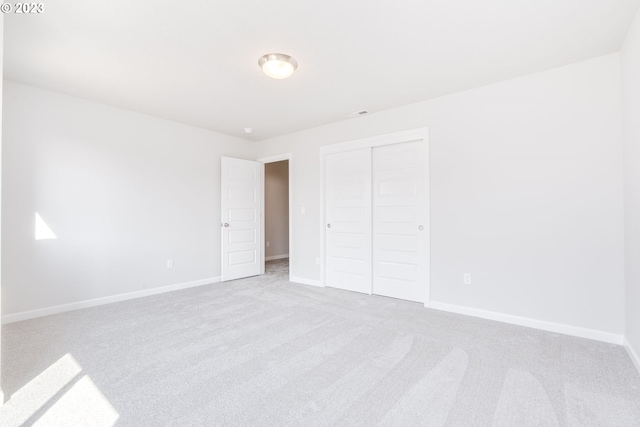 unfurnished bedroom featuring light colored carpet and a closet