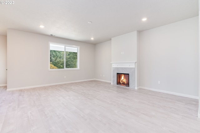 unfurnished living room featuring a high end fireplace and light hardwood / wood-style flooring