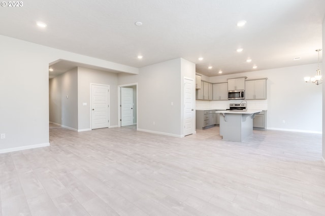 unfurnished living room featuring a chandelier and light hardwood / wood-style flooring