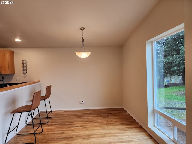 kitchen featuring a wealth of natural light, light wood-style flooring, pendant lighting, and a breakfast bar