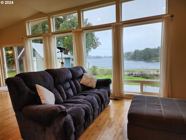 living area featuring light wood-style floors, a water view, lofted ceiling, and visible vents